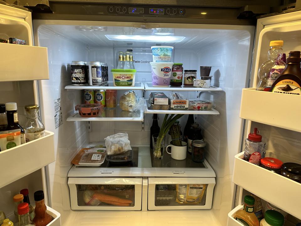 Open refrigerator stocked with various food items including dairy, produce, and condiments