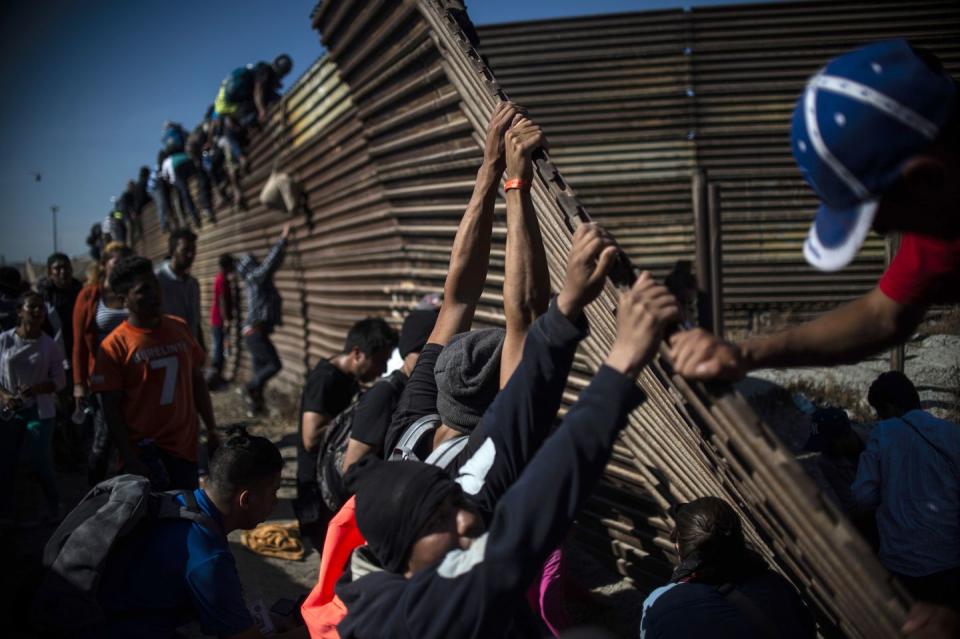 <p>A group of Central American migrants -mostly Hondurans- climb the border fence between Mexico and the United States as others try to bring it down, near El Chaparral border crossing, in Tijuana, Baja California State, Mexico, on November 25, 2018.</p>