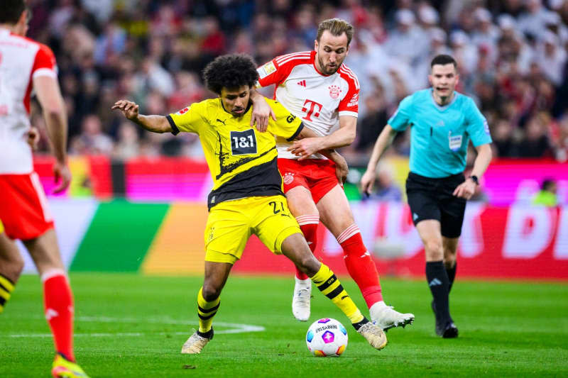 Dortmund's Karim Adeyemi (L) in action against Munich's Harry Kane during German Bundesliga soccer match between Bayern Munich and Borussia Dortmund at the Allianz Arena. Tom Weller/dpa