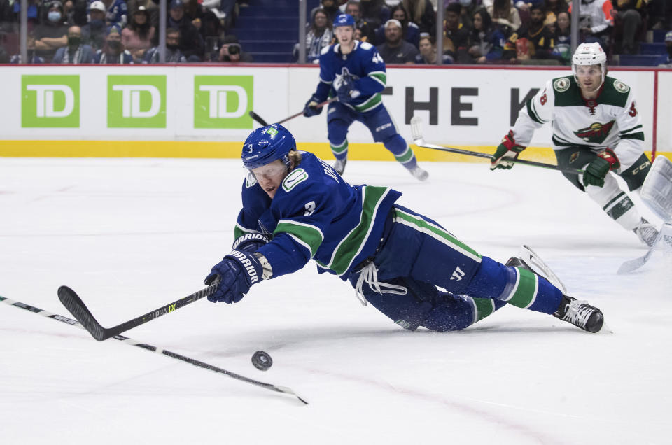 Vancouver Canucks' Jack Rathbone stumbles as he reaches for the puck during the first period of an NHL hockey game against the Minnesota Wild, Tuesday, Oct. 26, 2021 in Vancouver, British Columbia. (Darryl Dyck/The Canadian Press via AP)