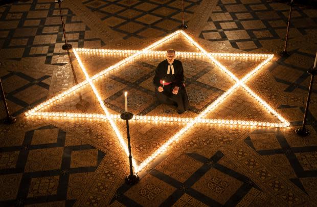 York Press: The Reverend Canon Michael Smith, Acting Dean of York, helps light six hundred candles in the shape of the Star of David, in memory of more than 6 million Jewish people murdered by the Nazis in the Second World War, in the Chapter House at York Minster