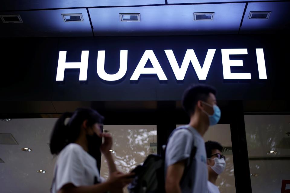 FILE PHOTO: People wearing face masks following the coronavirus disease (COVID-19) outbreak walk past a Huawei store at a shopping mall in Shanghai, China July 14, 2020. REUTERS/Aly Song
