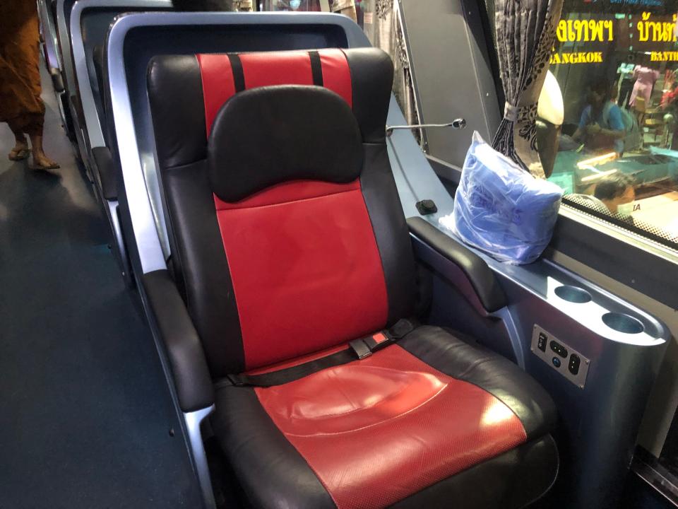 Red leather bus seat with massage tools in it 