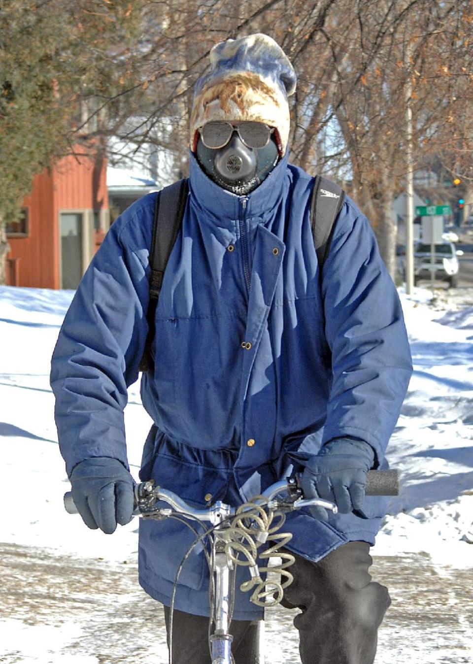 Jon Kramer, of Bismarck said a good way to beat the cold conditions is with a face mask called the cold avenger. Kramer uses the unusual looking face mask to break the wind as he rides his bicycle Monday Jan. 6, 2014. (AP Photo/The Tribune, Tom Stromme)