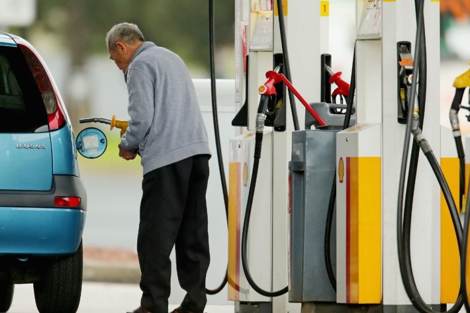 Elderly man fills up his car with petrol.