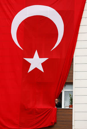 A man looks behind a national flag as Turkish President Tayyip Erdogan makes a speech during a ceremony in Istanbul, Turkey, March 26, 2017. REUTERS/Murad Sezer