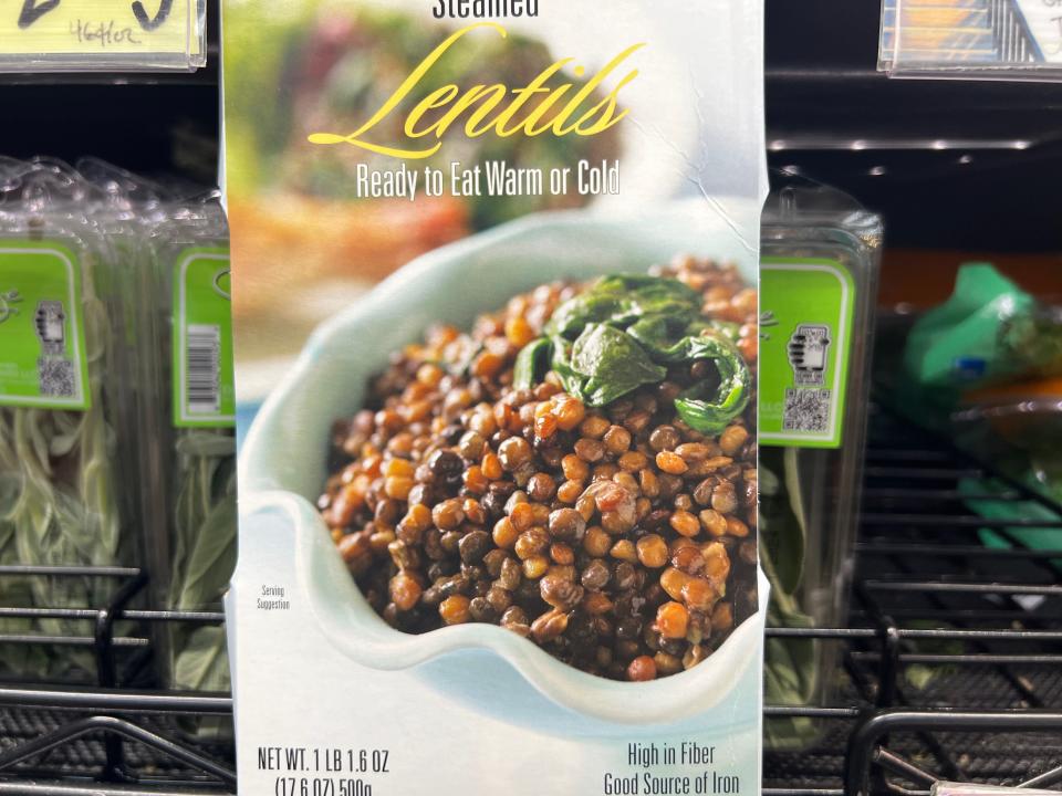 A box with a picture of a white bowl of steamed lentils garnished with herbs. The box says "Lentils ready to eat warm or cold"