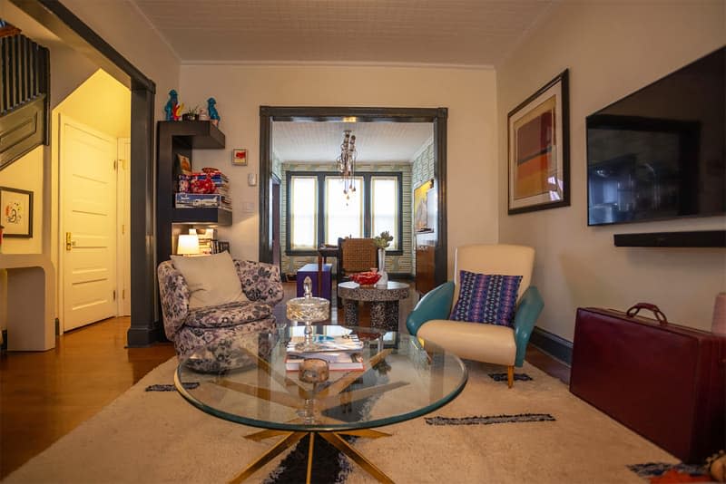 Glass coffee table in living room with mix matched arm chairs.