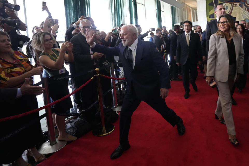 Brazilian President Luiz Inacio Lula da Silva greets journalists as he arrives at Congress for a ceremony to mark the one year anniversary since rioters stormed government buildings in support of outgoing, former President Jair Bolsonaro, in Brasilia, Brazil, Monday, Jan. 8, 2024. Rioters stormed the presidential palace, Congress and the Supreme Court buildings, and Bolsonaro has been under investigation by the Supreme Court over his role in the mayhem. (AP Photo/Eraldo Peres)