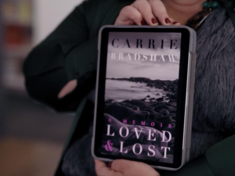 carrie's publisher holding up a cover option in and just like that