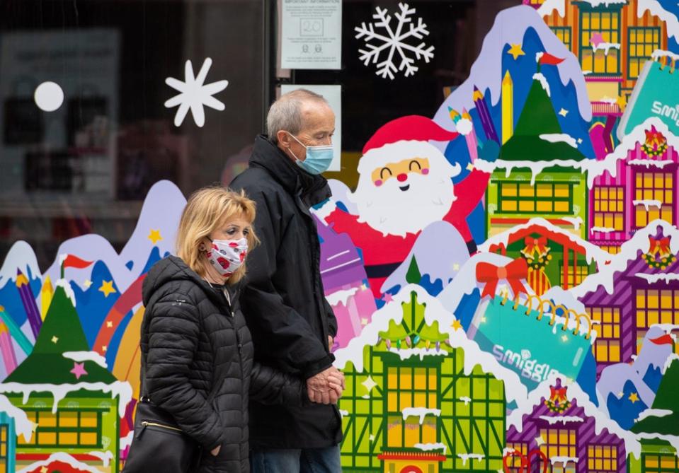 People wearing face masks pass a Christmas window display on Oxford Street, London (Dominic Lipinski/PA) (PA Archive)