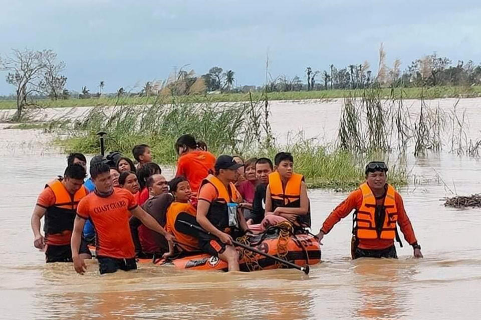 CORRECTS THE AREA TO NEGROS OCCIDENTAL, INSTEAD OF LOBOC, BOHOL - In this photo provided by the Philippine Coast Guard, rescuers pull a rubber boat as they assist residents who were trapped in their homes after floodwaters caused by Typhoon Rai inundated their village in Negros Occidental, central Philippines on Friday, Dec. 17, 2021. The strong typhoon engulfed villages in floods that trapped residents on roofs, toppled trees and knocked out power in southern and central island provinces, where more than 300,000 villagers had fled to safety before the onslaught, officials said. (Philippine Coast Guard via AP)