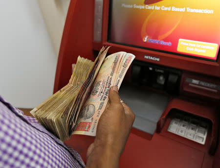 A customer deposits 1000 and 500 Indian rupee banknotes in a cash deposit machine at bank in Mumbai, India, November 8, 2016. REUTERS/Danish Siddiqui