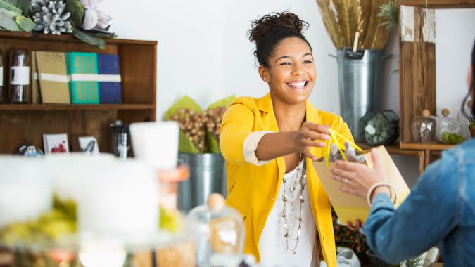 Saleswoman (16-17 years, mixed race African American) helping customer.