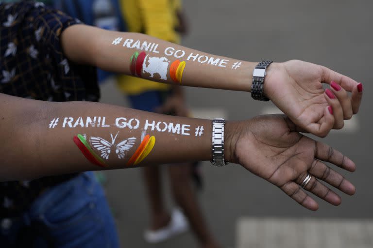 Dos mujeres muestran sus brazos con el mensaje "Ranil vete a casa", en alusión al exprimer ministro y actual presidente de Sri Lanka, Ranil Wickremesinghe, durante una protesta en Colombo, Sri Lanka, el 17 de julio de 2022. 
