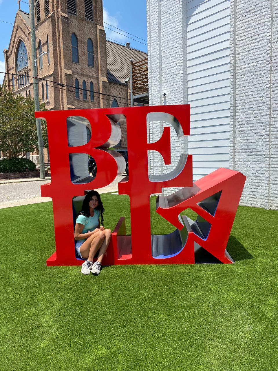 Bella Spinner, daughter of the developers and namesake of The Bella, poses with the monument sign on the front lawn.
