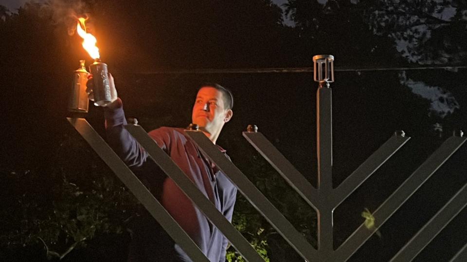 Brian Fox, who attends Chabad Lubavitch on Winkler Avenue in Fort Myers, lights the menorah Sunday along McGregor Boulevard heralding the start of the eight-day Jewish holiday of Hanukkah, symbolizing lighting the darkness.