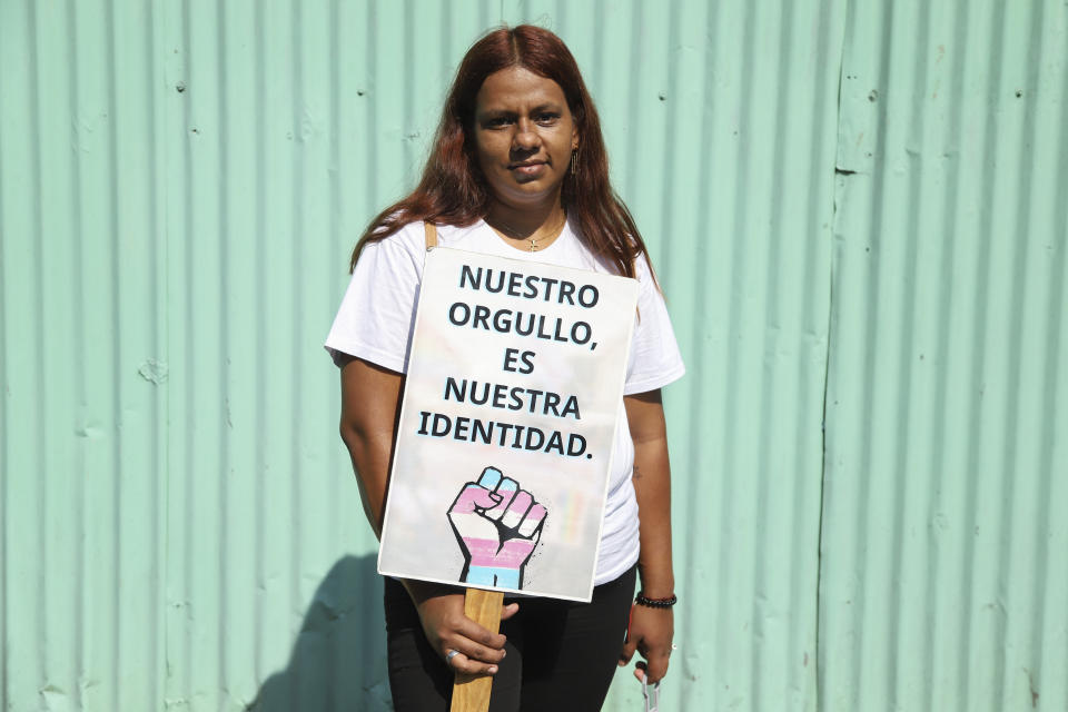 Denisse Menendez, who defines herself as a pansexual person, poses with a sign with a message that reads in Spanish; "Our pride is our identity," during a protest in front of Congress demanding the approval of a Gender Identity Law, marking the International Day Against Homophobia, Biphobia and Transphobia, a global call to protect the rights of LGBTQI+ people, in San Salvador, El Salvador, Wednesday, May 17, 2023. (AP Photo/Salvador Melendez)