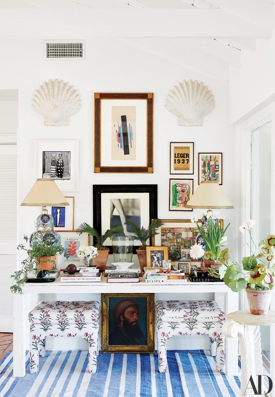 Artworks by Ilia Tchachnik, Malick Sidibé, and Fernand Léger hang above a custom table; the Palm Beach regency stools are covered in Brigitte Singh fabric.