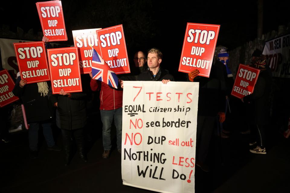 Loyalists protest outside the grounds were the Democratic Unionist Party executive meeting is taking place at Larchfield Estate in Lisburn, Northern Ireland, Monday, Jan. 29, 2024. The Unionist leader is meeting with his executive members to work on a deal to restore power-sharing at Stormont on Monday. The 130 strong-party executive was invited at short notice Monday to a secure venue as it is expected to be picked by Loyalist protesters opposed to returning to power. (AP Photo/Peter Morrison)