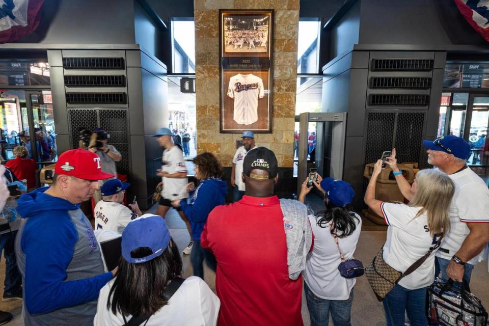 Texas Rangers fans take photos with the 2023 World Series commemorative plaque as they enter the stadium for the 2024 season opener between the Rangers and the Chicago Cubs at Globe Life Field in Arlington on Thursday, March 28, 2024. Chris Torres/ctorres@star-telegram.com