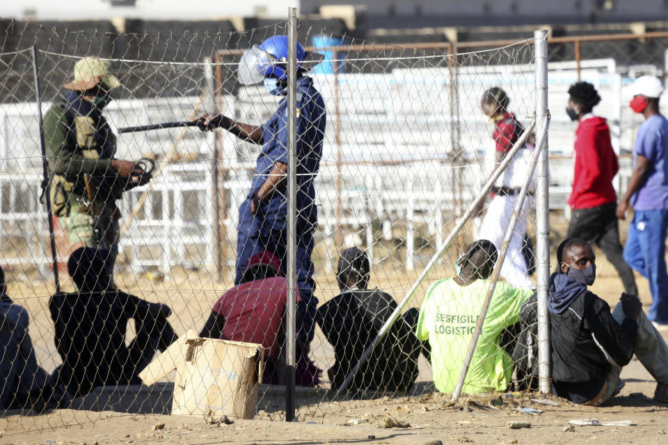 Zimbabwean police and army roundup people at a checkpoint in Harare, Thursday, July, 30, 2020. Zimbabwe's capital, Harare, was deserted Thursday, as security agents vigorously enforced the country's lockdown ahead of anti government protests planned for Friday. Police and soldiers manned checkpoints and ordered hundreds of people seeking to get into the city for work and other chores to return home.(AP Photo/Tsvangirayi Mukwazhi)