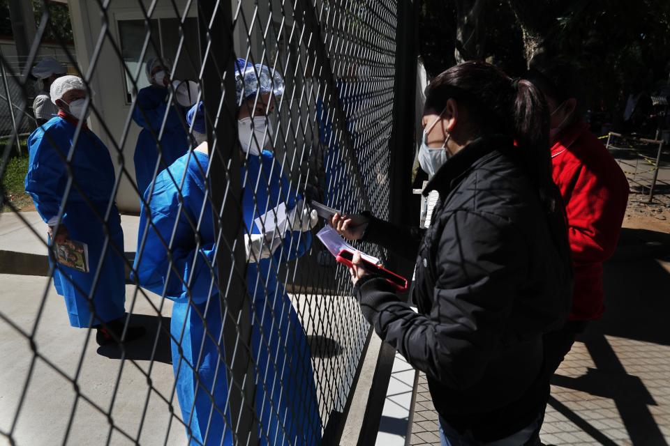 The relative of a COVID-19 patient hospitalized at Ineram Hospital's ICU, is given a list of prescription medication to buy from a doctor through the hospital fence in Asuncion, Paraguay, Monday, May 24, 2021. (AP Photo/Jorge Saenz)