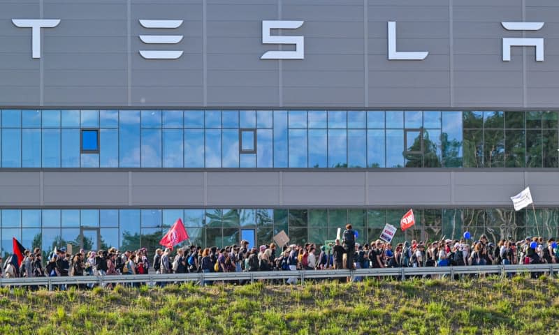 Environmental activists walk past the Tesla plant during a protest against Tesla. After sometimes violent clashes on May 10, 2024 at the Tesla factory site in Gruenheide near Berlin, new protests are currently underway against the US company. Patrick Pleul/dpa