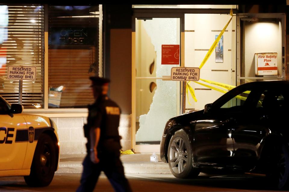 A police officer walks in front of shattered glass at Bombay Bhel restaurant (REUTERS)