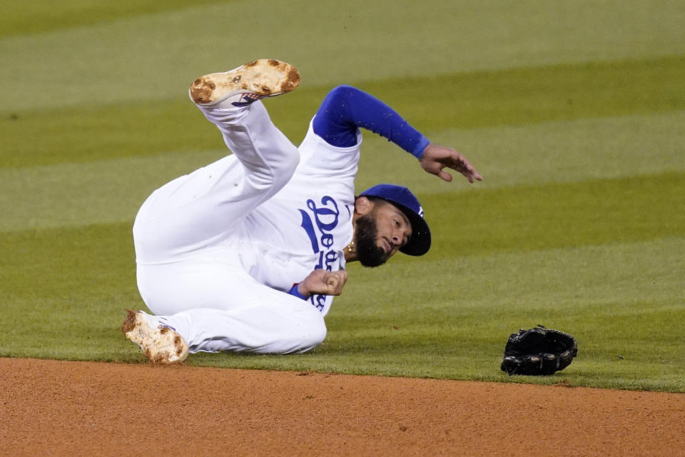 Los Angeles Dodgers third baseman Edwin Rios loses his glove after diving for a ball hit for a single by Cincinnati Reds' Jesse Winker during the fourth inning of a baseball game Monday, April 26, 2021, in Los Angeles. (AP Photo/Mark J. Terrill)