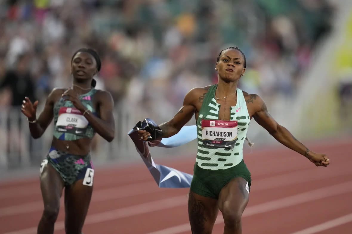 Sha’Carri Richardson grabs the tape as she wins the women’s 100 meter finals ahead of Tamara Clark during the U.S. track and field championships in Eugene, Ore., Friday, July 7, 2023. (AP Photo/Ashley Landis)