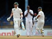 Australian batsmen Michael Clarke (L) and Ricky Ponting (R) run as West Indies bowler Kemar Roach (C) reacts during the fourth day of the second-of-three Test matches between Australia and West Indies April 18, 2012 at Queen's Park Oval in Port of Spain, Trinidad.