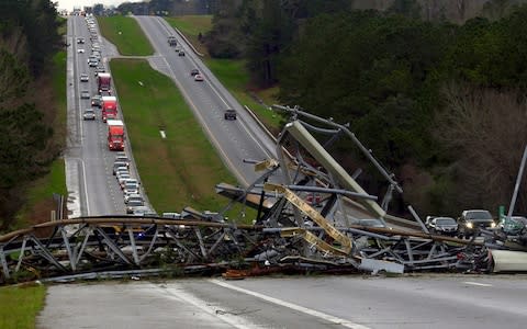 A fallen cell tower lies across U.S. Route 280 highway in Lee County, Alabama - Credit: AP