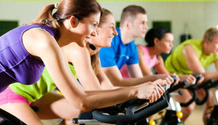 Group of five people in gym or fitness club exercising their legs doing cardio training