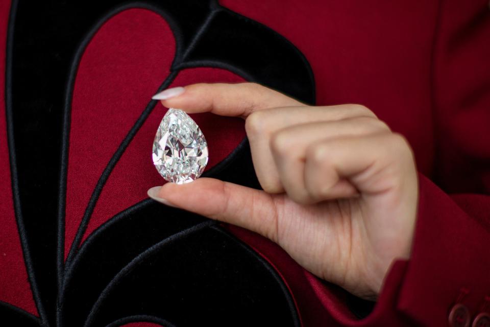 An employee of Sotheby's poses with a rare pear-Shaped D Colour Flawless 100+ carat diamond at Sotheby's in New York City, New York, US, 21 June, 2021 (REUTERS)