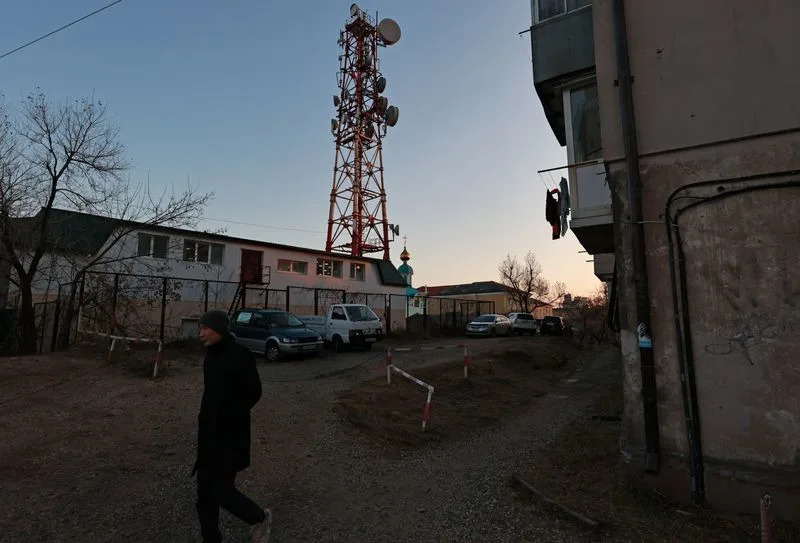A man walks past a communication tower in Vladivostok