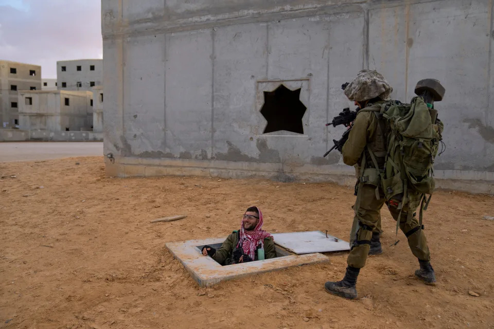 Israeli soldiers aim their weapons toward their colleague dressed as a Palestinian militant, while he exits from a fake tunnel, during training session simulating urban fighting at the Zeelim army base, southern Israel, Jan. 4, 2022.