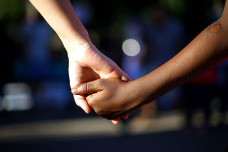 A volunteer holds the hand of an Haitian immigrant child at a church in Santiago, Chile, December 18, 2016. Picture taken December 18, 2016. REUTERS/Ivan Alvarado
