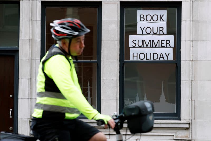 Man rides a bicycle past a travel agents store, in Manchester