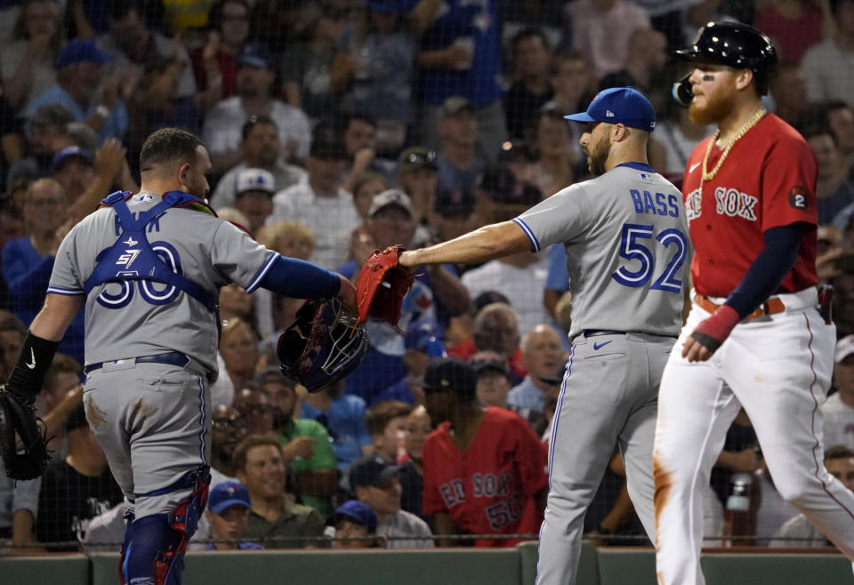 Toronto Blue Jays relief pitcher Anthony Bass (52) is congratulated by catcher Alejandro Kirk as Boston Red Sox's Alex Verdugo (99) returns to the dugout after Bass struck out Bobby Dalbec with the bases loaded to end the eighth inning of a baseball game at Fenway Park, Wednesday, Aug. 24, 2022, in Boston. (AP Photo/Mary Schwalm)