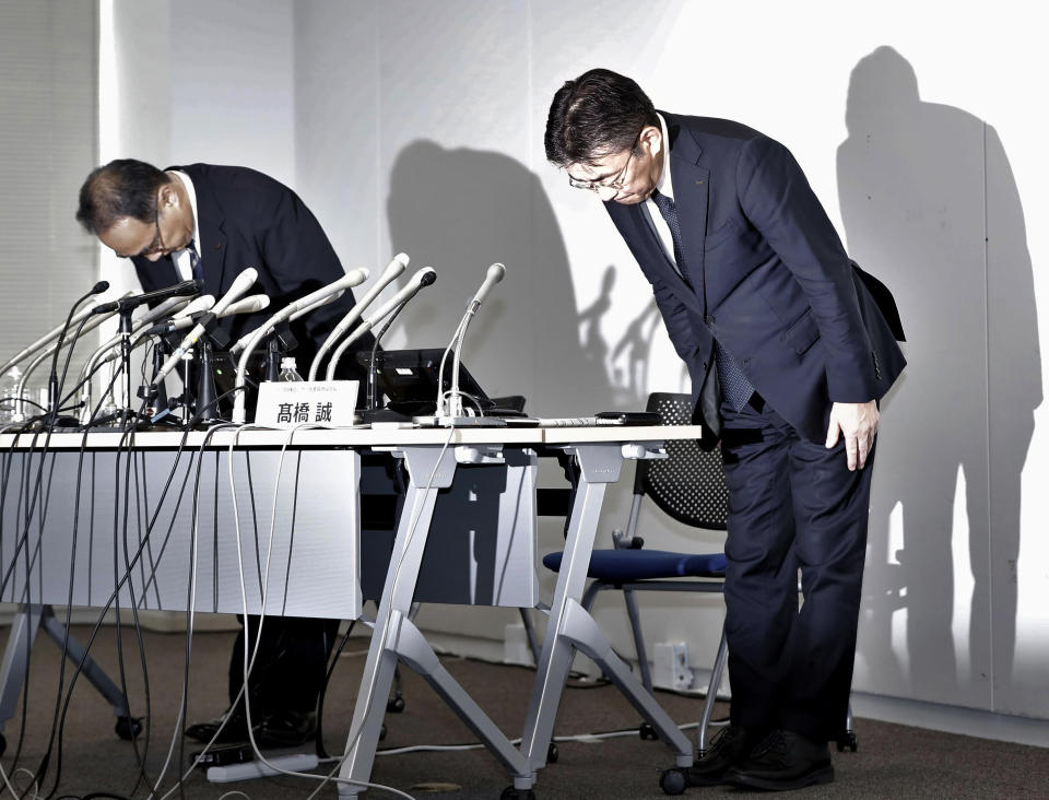 KDDI Corp. President Makoto Takahashi, right, bows at the end of a press conference in Tokyo Sunday, July 3, 2022. A weekend outage at Japan’s No. 2 mobile carrier KDDI Corp. was still preventing many of its customers from making calls Monday. The massive outage that began early Saturday affected nearly 40 million people and the delivery of weather reports and other services across the country. (Kyodo News via AP)