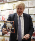 Britain's Prime Minister Boris Johnson holds a gift card with an image mocking him, during a General Election campaign stop in Wells, England, Thursday, Nov. 14, 2019. Britain goes to the polls on Dec. 12. (AP Photo/Frank Augstein, Pool)