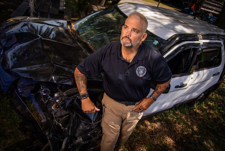 Ocala Police Sgt. Ron Malone leans against the Ocala Police unit he was driving in August 2023 when he was seriously injured in a crash.