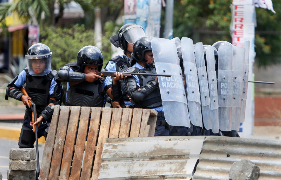 FILE - In this April 20, 2018 file photo, a Nicaraguan police officer aims his weapon at protesting students during a third day of violent clashes in Managua, Nicaragua. The Madres de Abril (Spanish for Mothers of April) group is gearing up for a potentially years-long fight against the government of Nicaraguan President Daniel Ortega in its quest for accountability and justice for the hundreds of people killed in the government suppression of protests since April 2018.(AP Photo/Alfredo Zuniga, File)