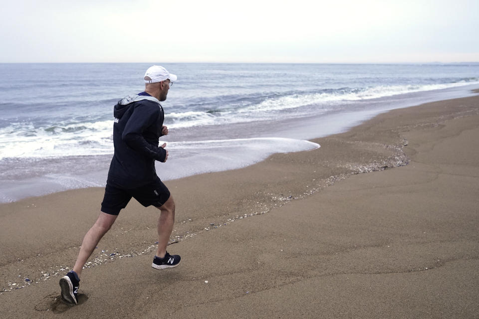 Dave Fortier, of Newburyport, Mass., president of One World Strong Foundation, trains for the 2023 Boston Marathon on a beach Tuesday, April 4, 2023, in Newburyport. Fortier was hit in the foot by shrapnel in the 2013 bombing and doesn't remember finishing the race. (AP Photo/Steven Senne)