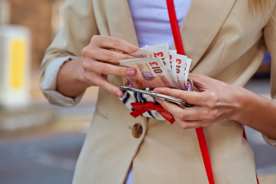 Close up of woman's hands counting pounds in her wallet.