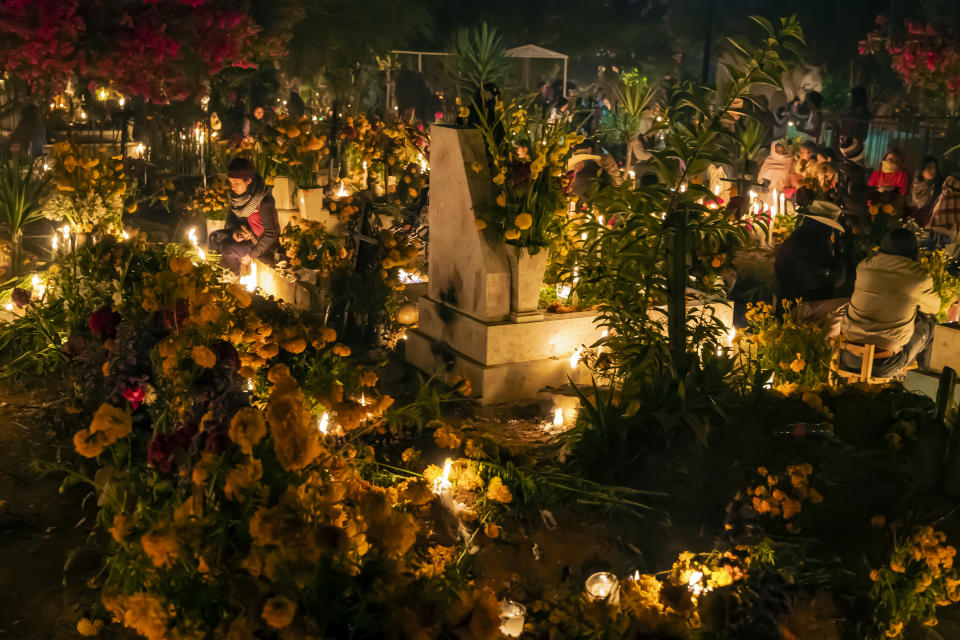 Cemetery in San Agustin Etla, Oaxaca, Mexico– November 1, 2018: People holding vigils at the graves of relatives as part of the celebration of the Día de los Muertos. Graves are cleaned, decorated with flowers (typically featuring marigolds), skulls, candles, and often with the deceased's favorite food and liquor. This annual holiday is celebrated extensively in southern Mexico with face painting, costumes, parades, dancing, altars, and graveside vigils. Celebration of the Día de los Muertos has been adopted in many other parts of the world.