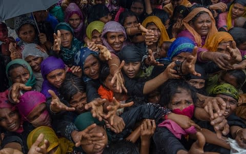 Rohingya Muslim women reach up to get sanitary products distributed by aid agencies - Credit: AP Photo/Dar Yasin