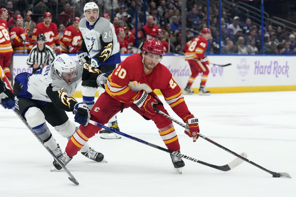 Calgary Flames center Blake Coleman (20) skates around Tampa Bay Lightning defenseman Haydn Fleury (7) during the first period of an NHL hockey game Thursday, Nov. 17, 2022, in Tampa, Fla. (AP Photo/Chris O'Meara)