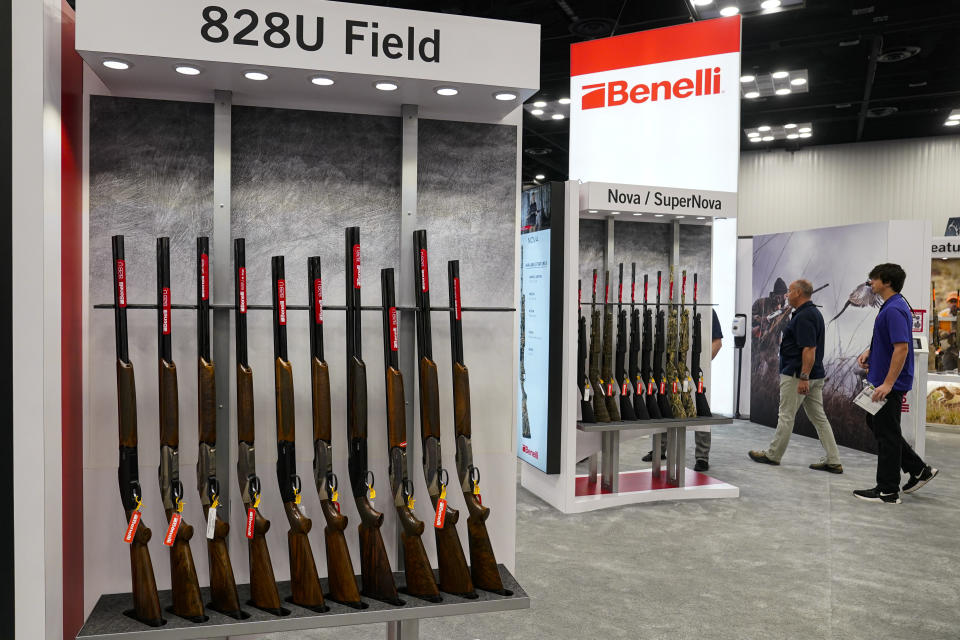 FILE - Guests browse firearms in the Benelli display area at the National Rifle Association's Annual Meetings & Exhibits in Indianapolis, April 16, 2023. The roster of Republican presidential hopefuls who flocked to the National Rifle Association's annual convention reflects the political potency of gun rights, despite the group's eroding revenues and an opposition movement that's growing increasingly vocal as the drumbeat of mass shootings marches on. (AP Photo/Michael Conroy)